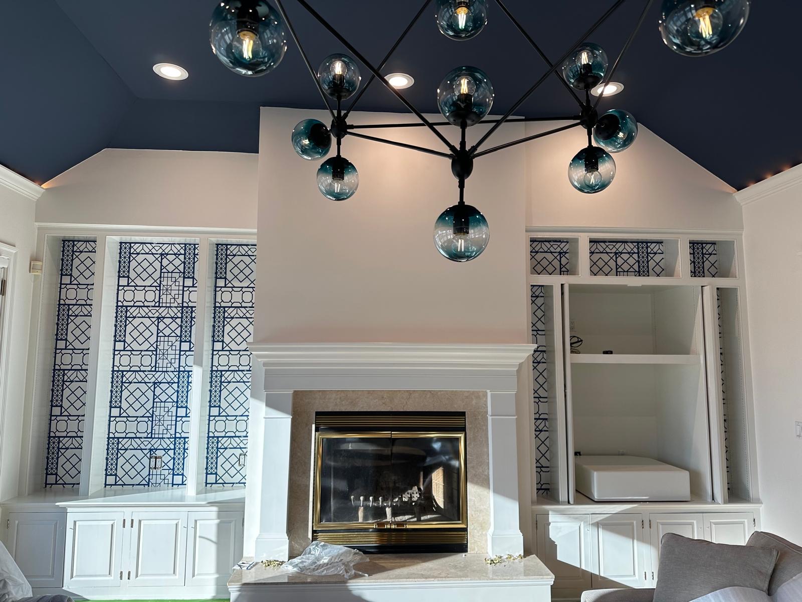 Blue lattice wallpaper inside built-in shelves beside a fireplace