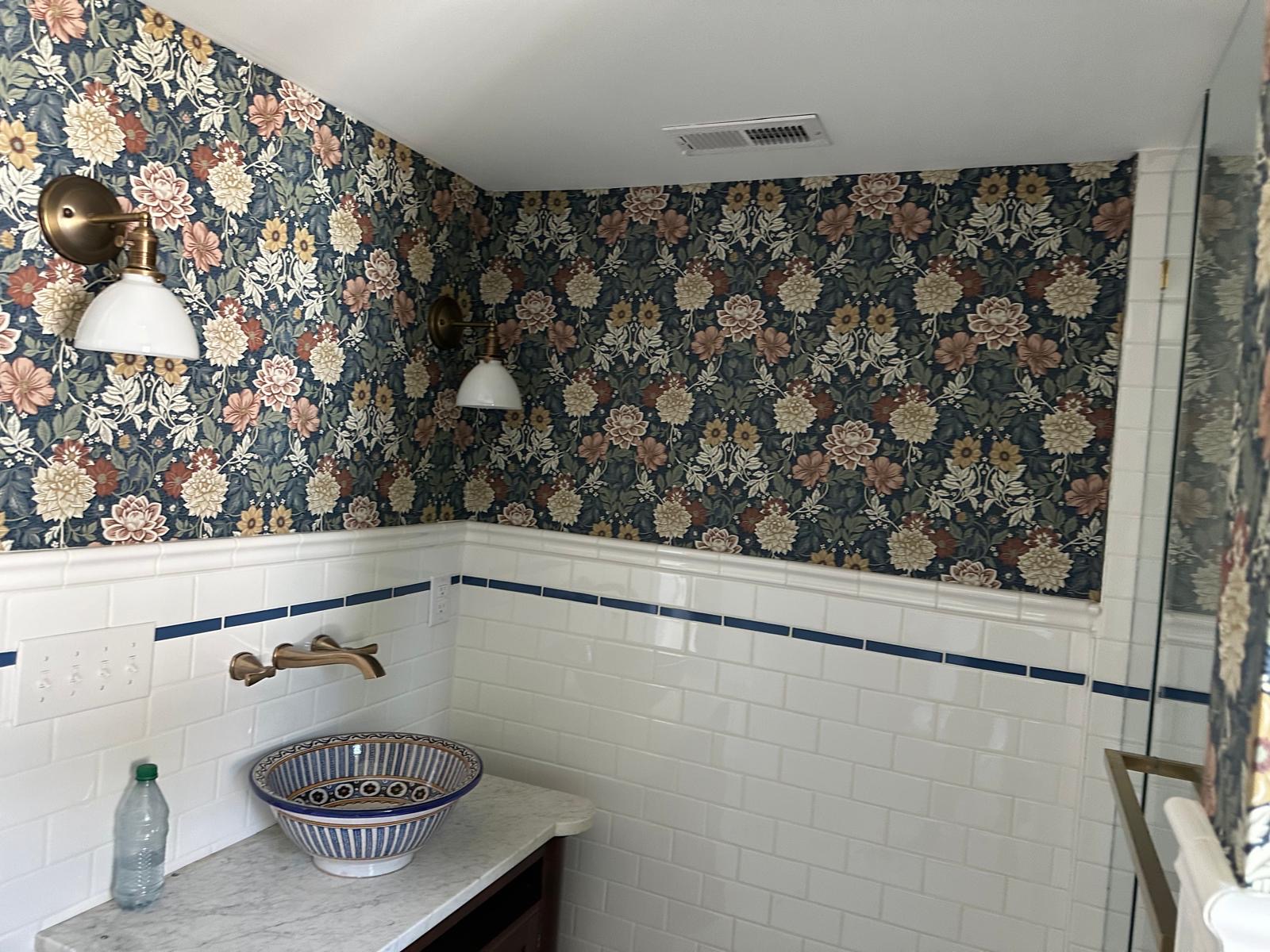 Navy floral wallpaper above white subway tile in a bathroom