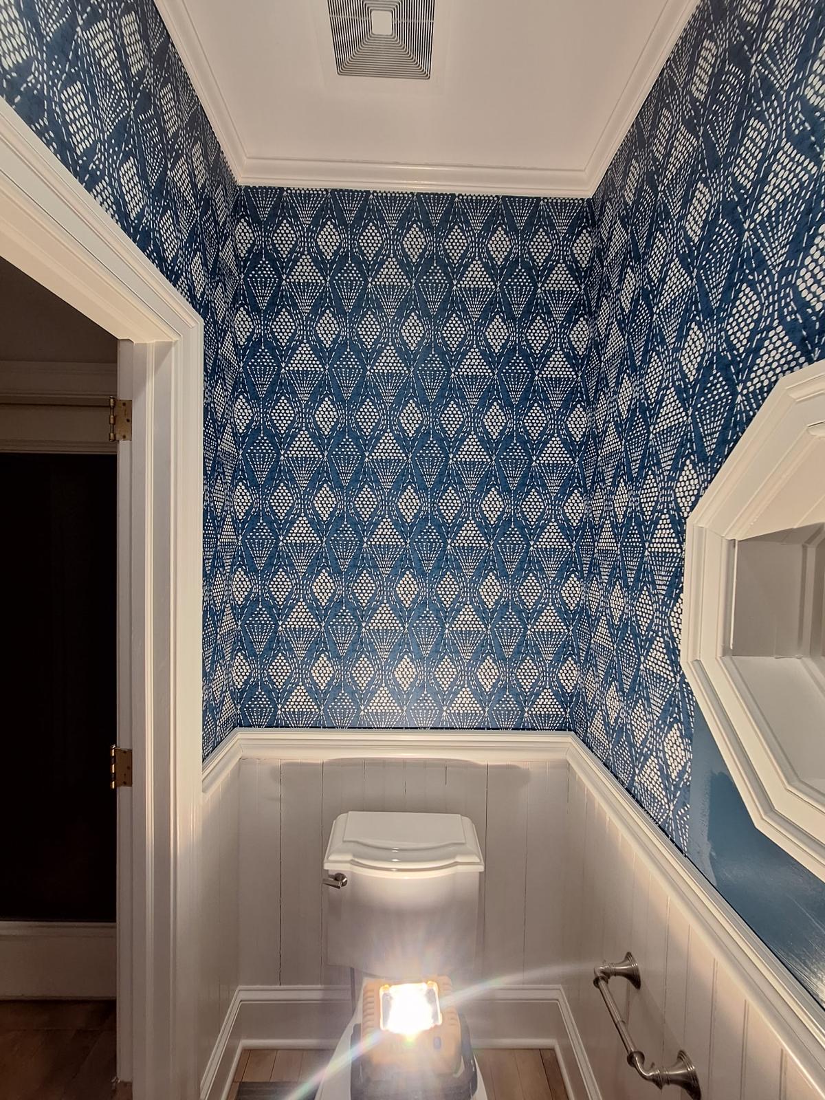 Blue geometric wallpaper above white wainscoting