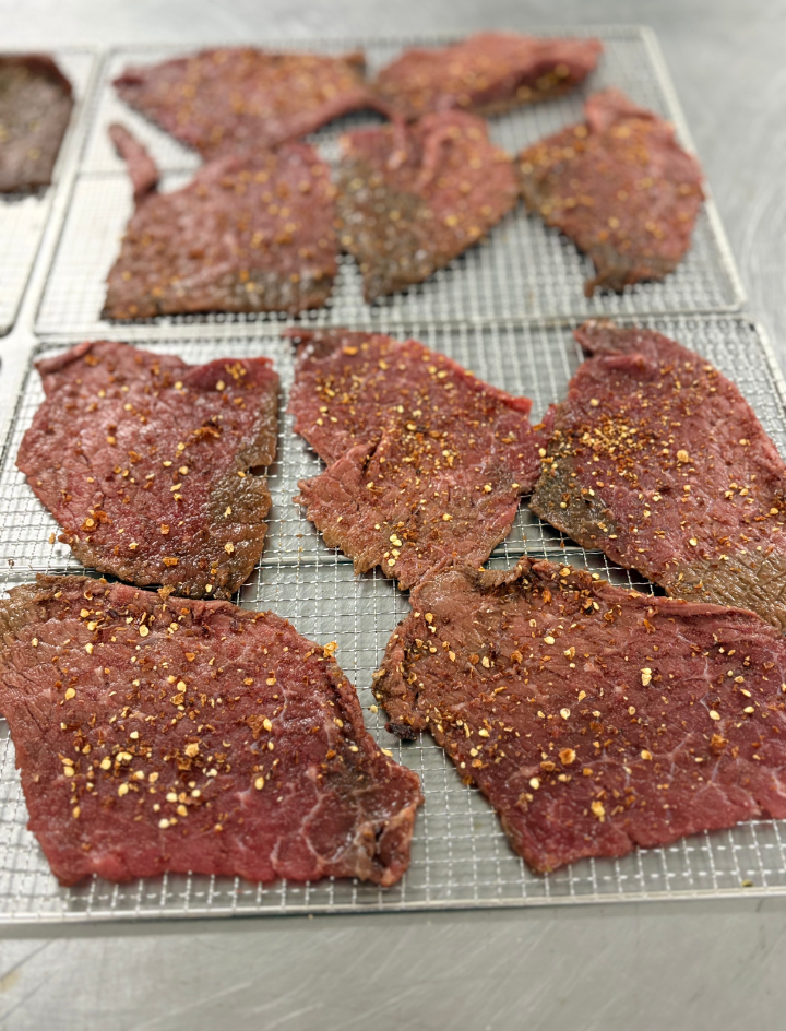 Fresh seasoned jerky on a drying rack