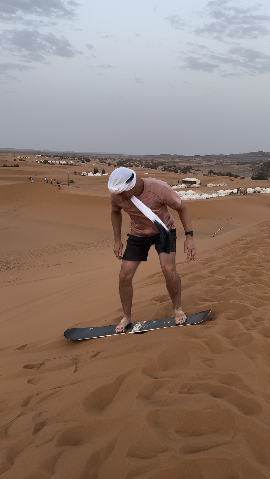 Sandboarding down a dune in the Sahara Desert