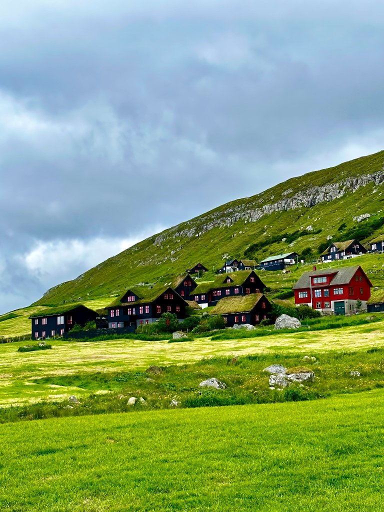 Village nestled at the foot of a green mountainside, Faroe Islands