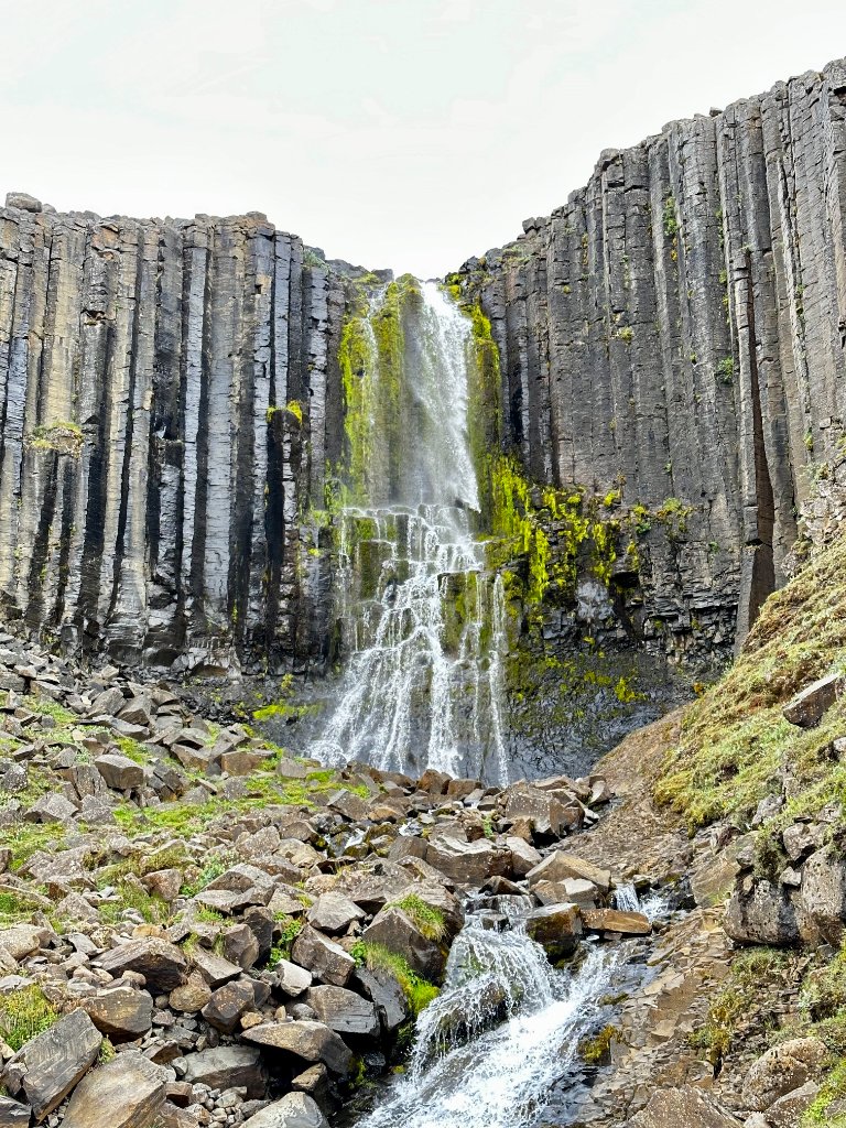 A waterfall flowing through the basalt columns of Stuðlagil Canyon in Iceland