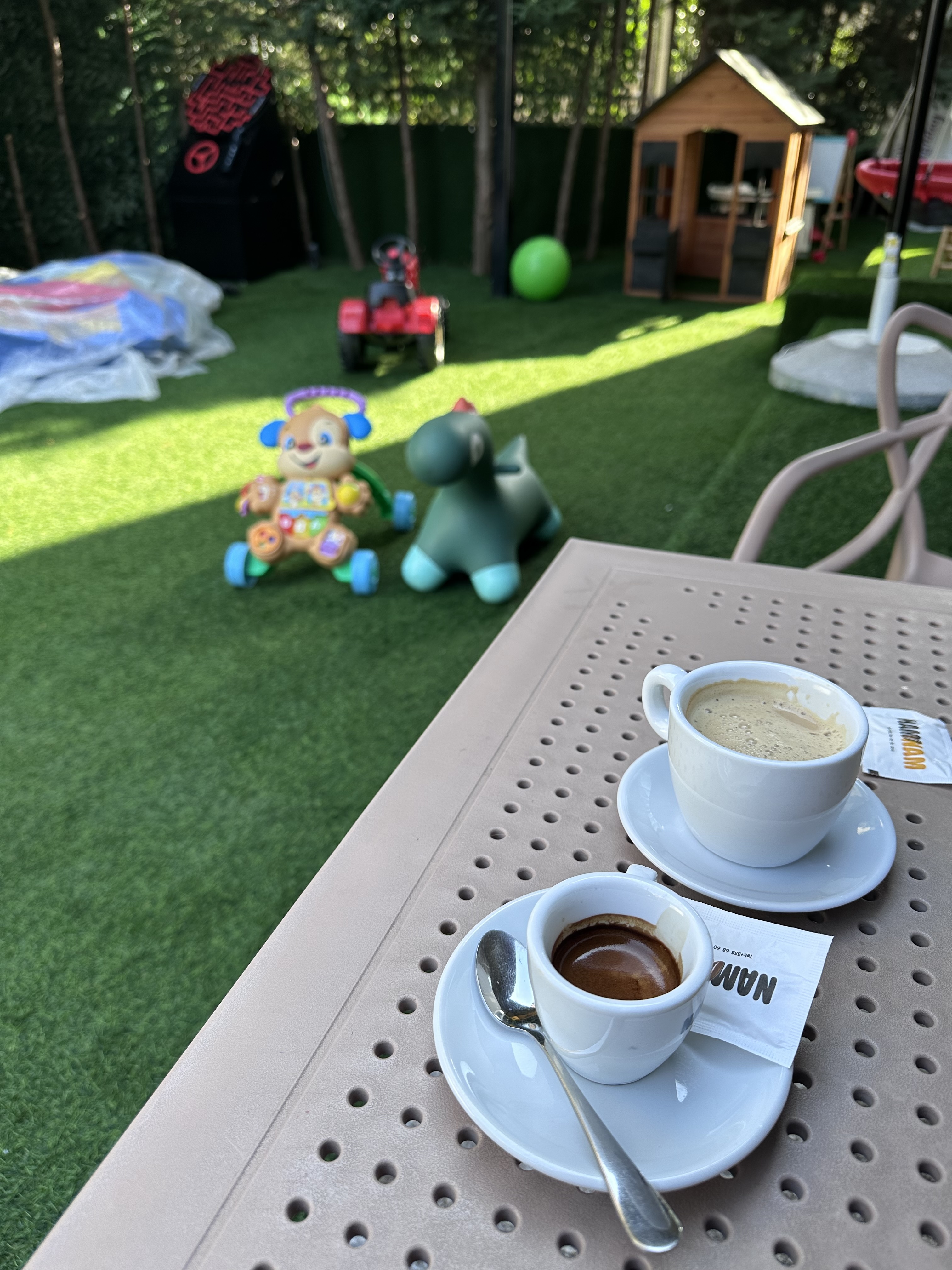 Outdoor café table with coffee cups beside a kids' playground in Tirana