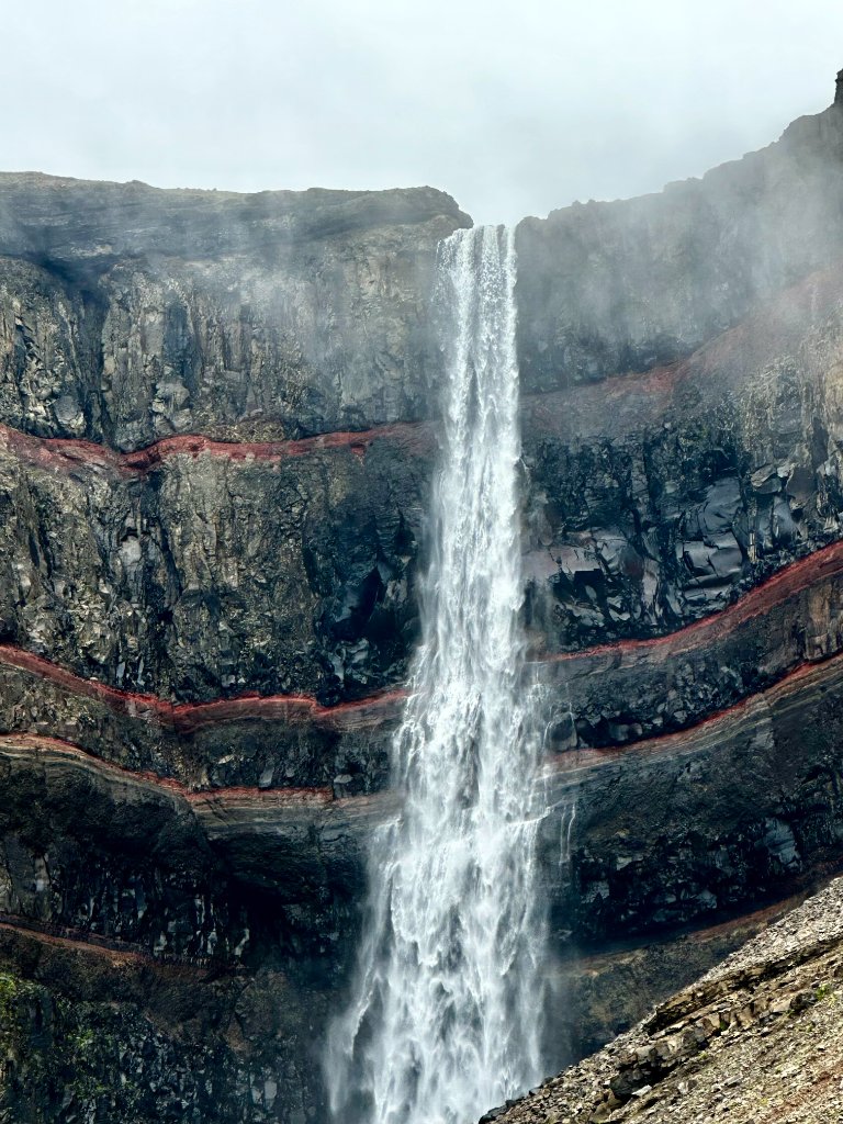 Hengifoss waterfall cascading down a layered rock face with red volcanic bands