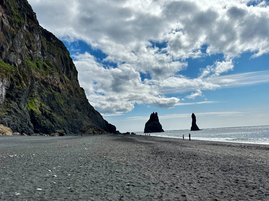 Reynisfjara black sand beach in Iceland with basalt sea stacks rising from the ocean