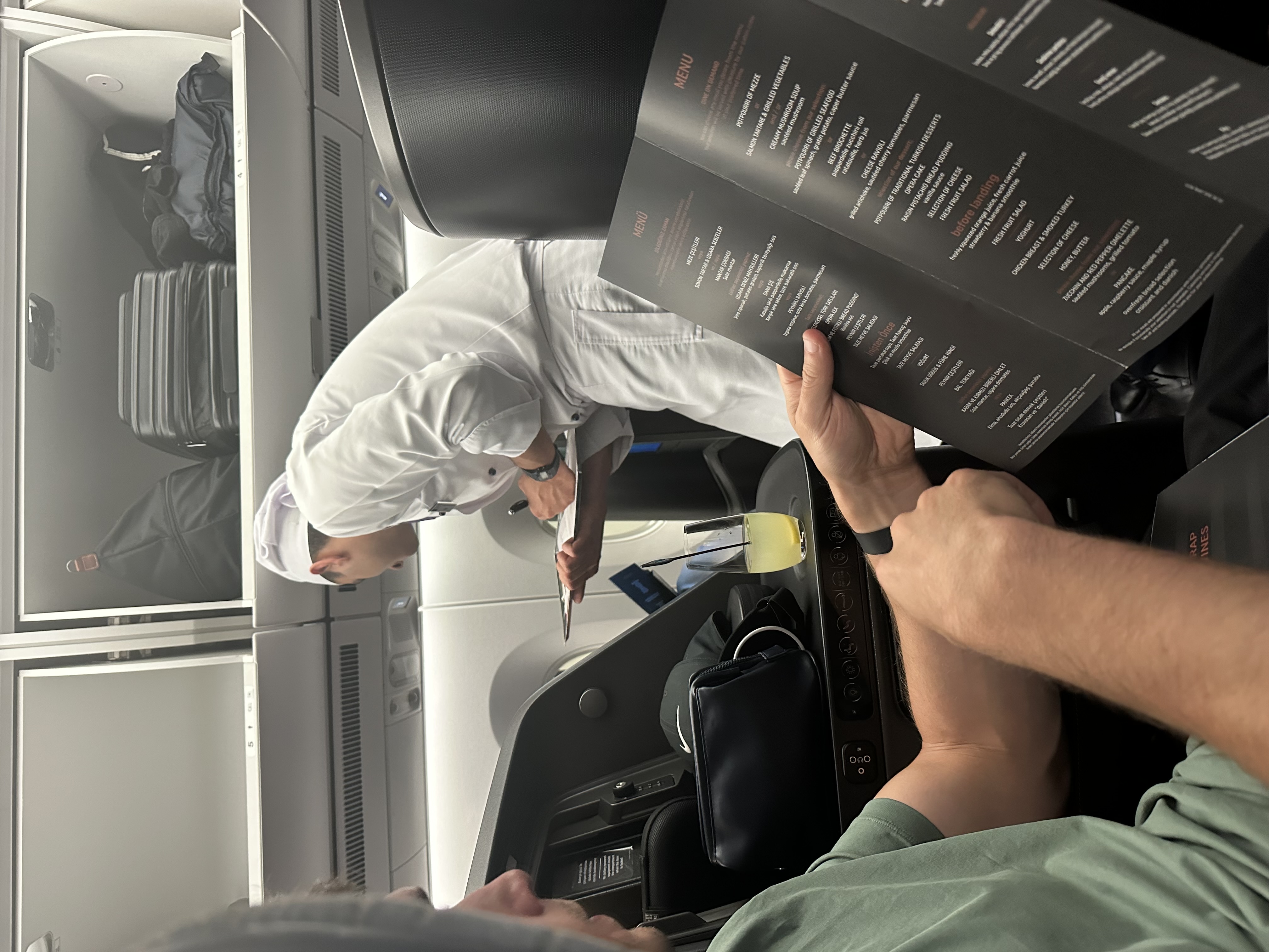 Cabin crew member taking a passenger's order from the business class menu