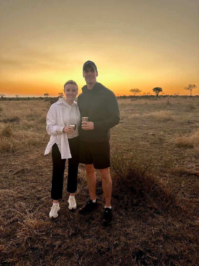 A couple enjoying sunset drinks in an open South African savanna