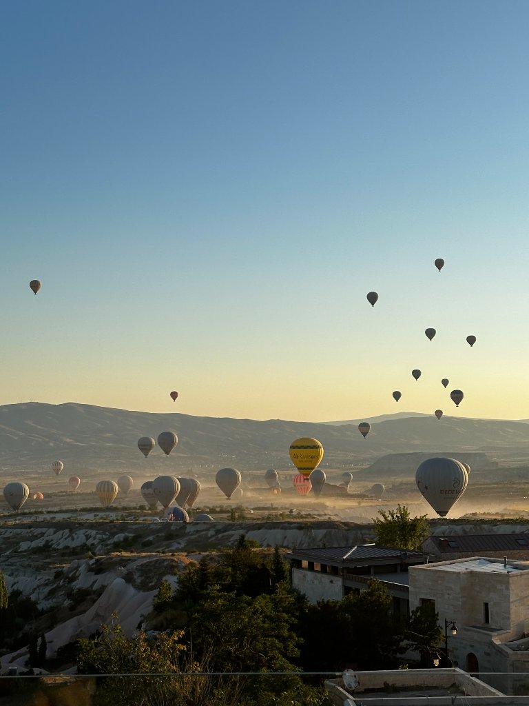 Hot air balloons scattered across the Cappadocia sky at sunrise