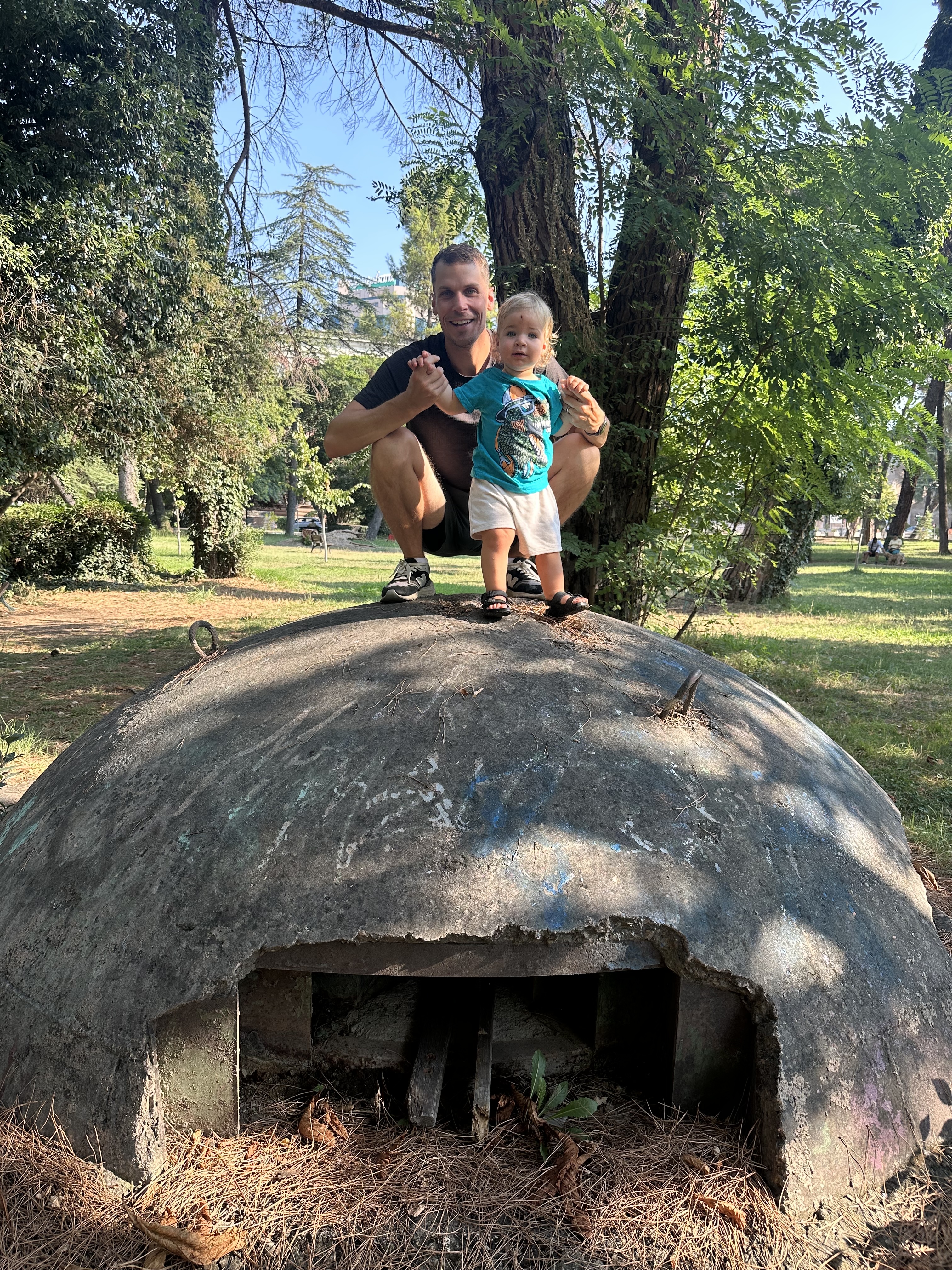 Man and child standing on a concrete bunker in an Albanian park