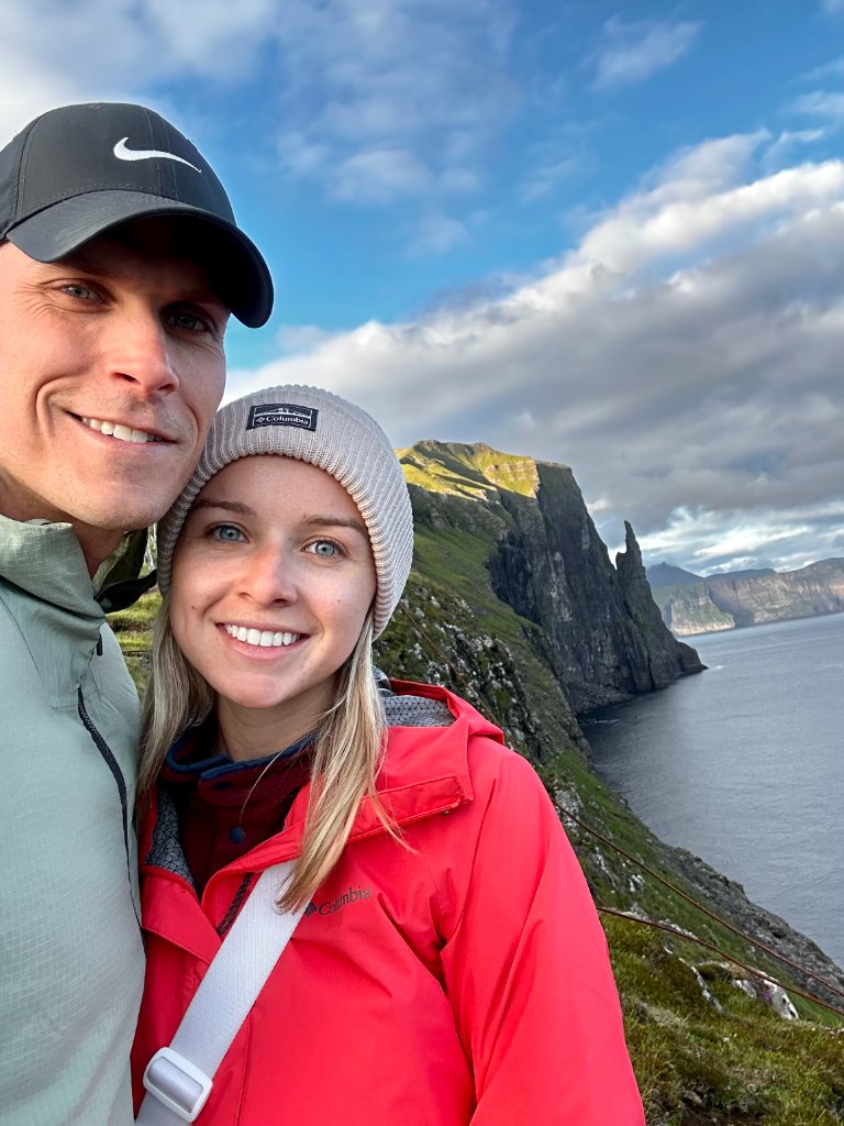 Couple smiling with dramatic Faroe cliffs behind