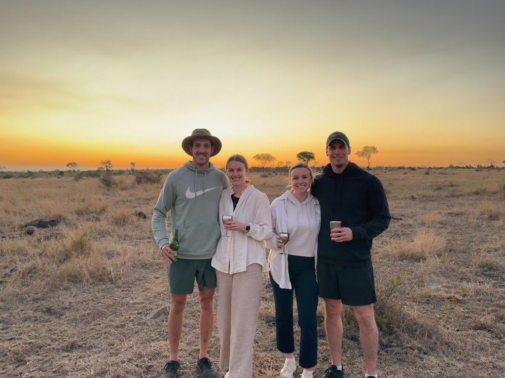 Four travellers standing together in a dry South African savanna at sunset