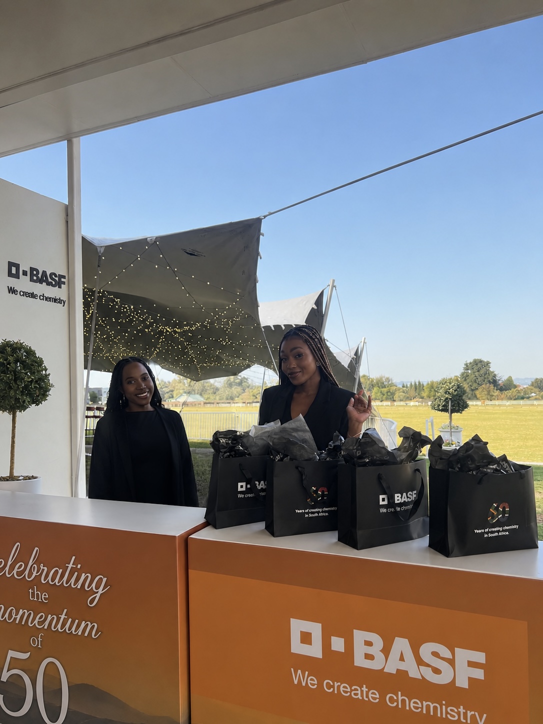 MRJ registration staff handing out branded BASF 60th anniversary gift bags at the welcome desk