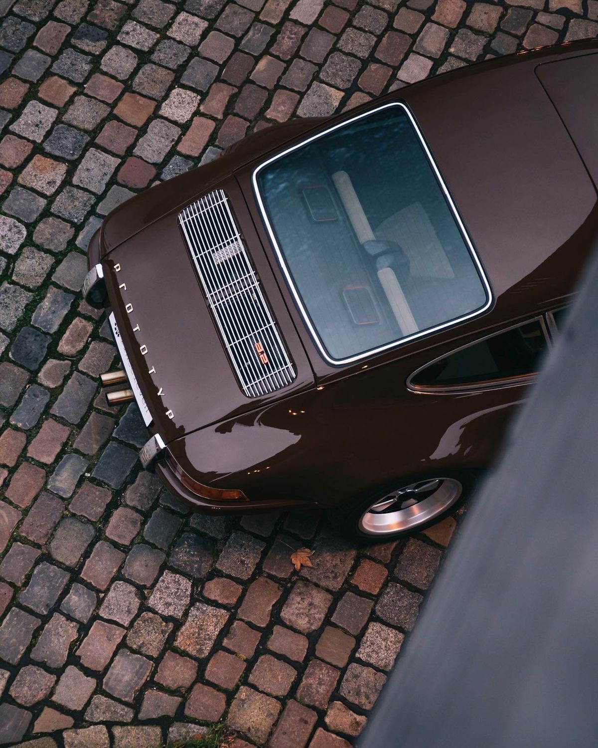 Brown Porsche 911 photographed from above on cobblestone