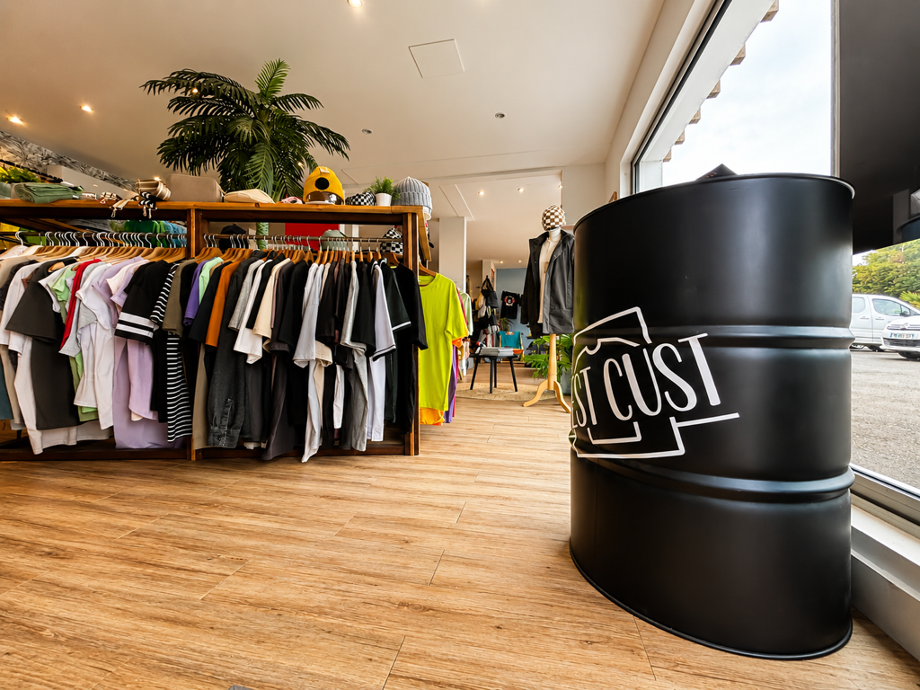 Showroom West Cust, fût de branding, racks de tee-shirts colorés et coin détente