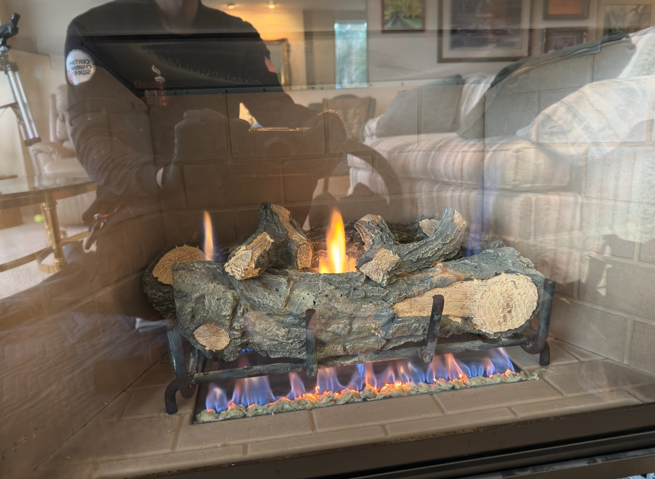 Gas fireplace with ceramic logs and pilot light flame visible through glass front