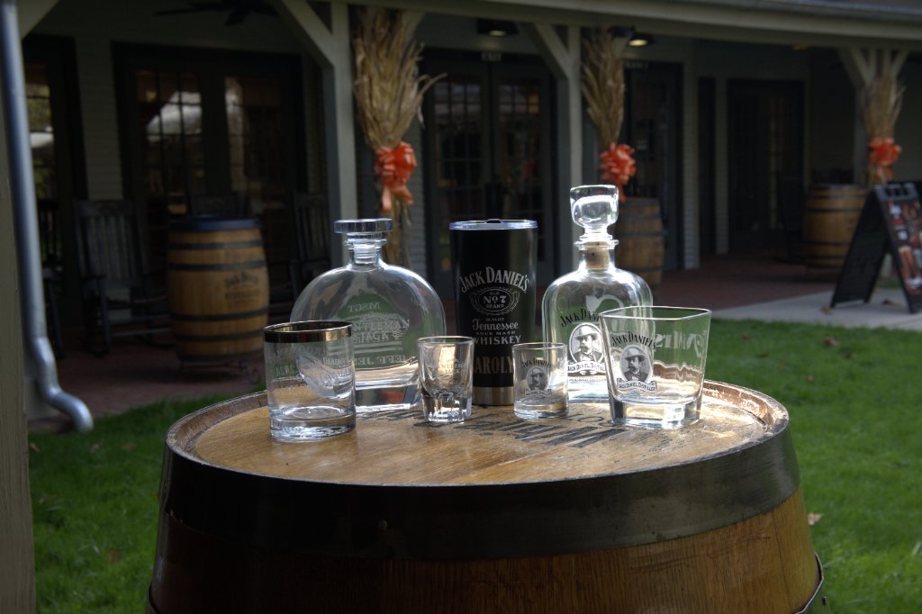 Engraved whiskey bottles, decanters, and glasses on a wooden barrel