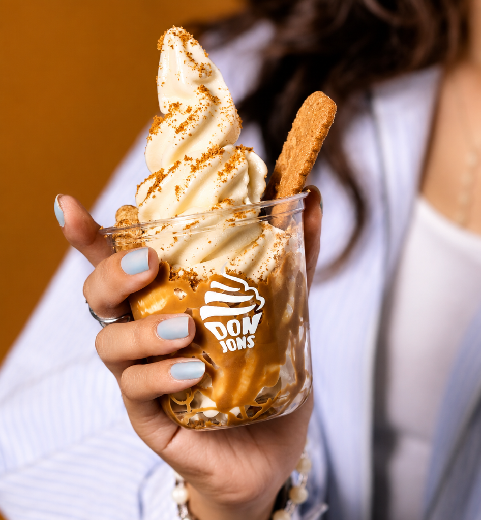Hand holding vanilla soft serve with biscuit