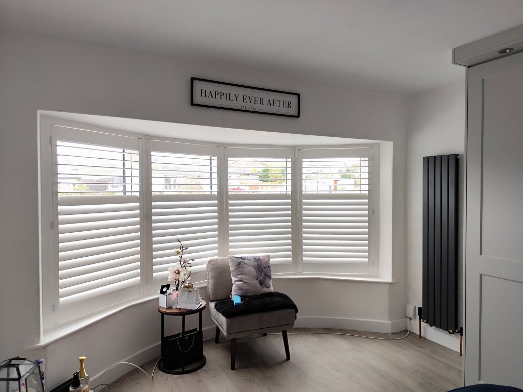 White plantation shutters in a modern bay window bedroom