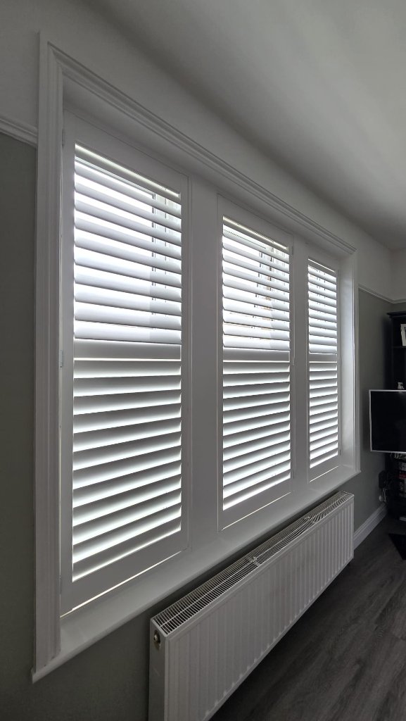 Triple-window white plantation shutters fitted in a Leeds living room