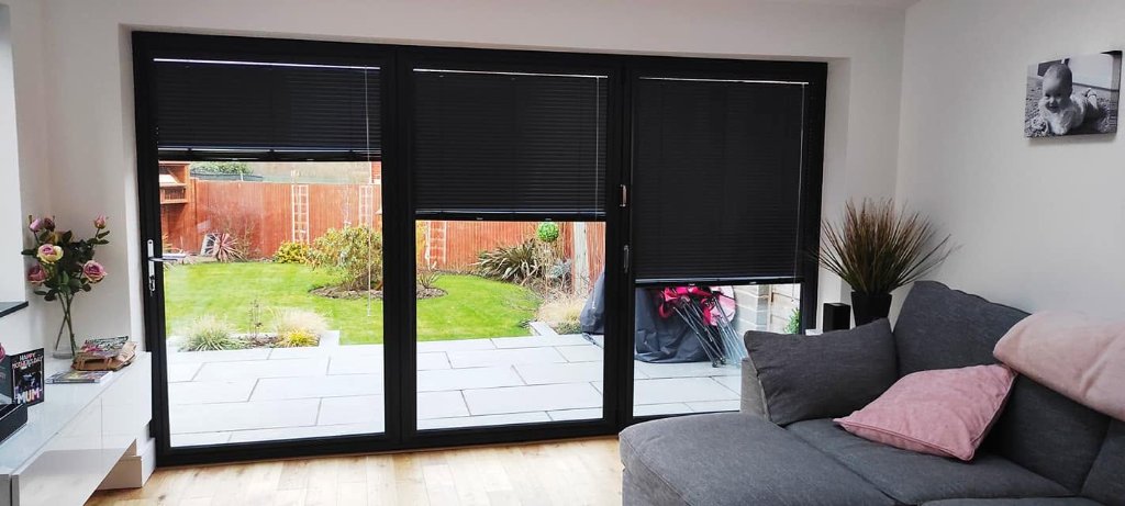 Dark pleated Venetian blinds fitted on bi-fold doors in a Leeds living room