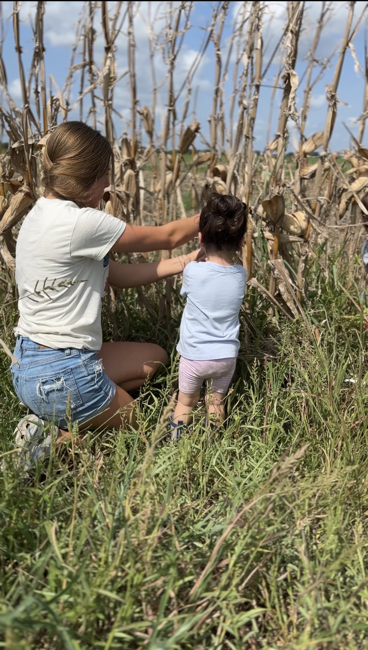 Adult and child picking corn together in the field