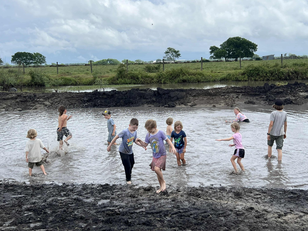 Children splashing in the farm mud pond