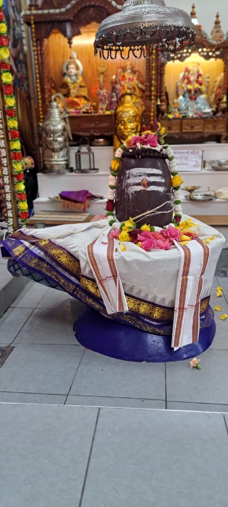 The Lingam draped in white and gold silk with a garland of fresh flowers.