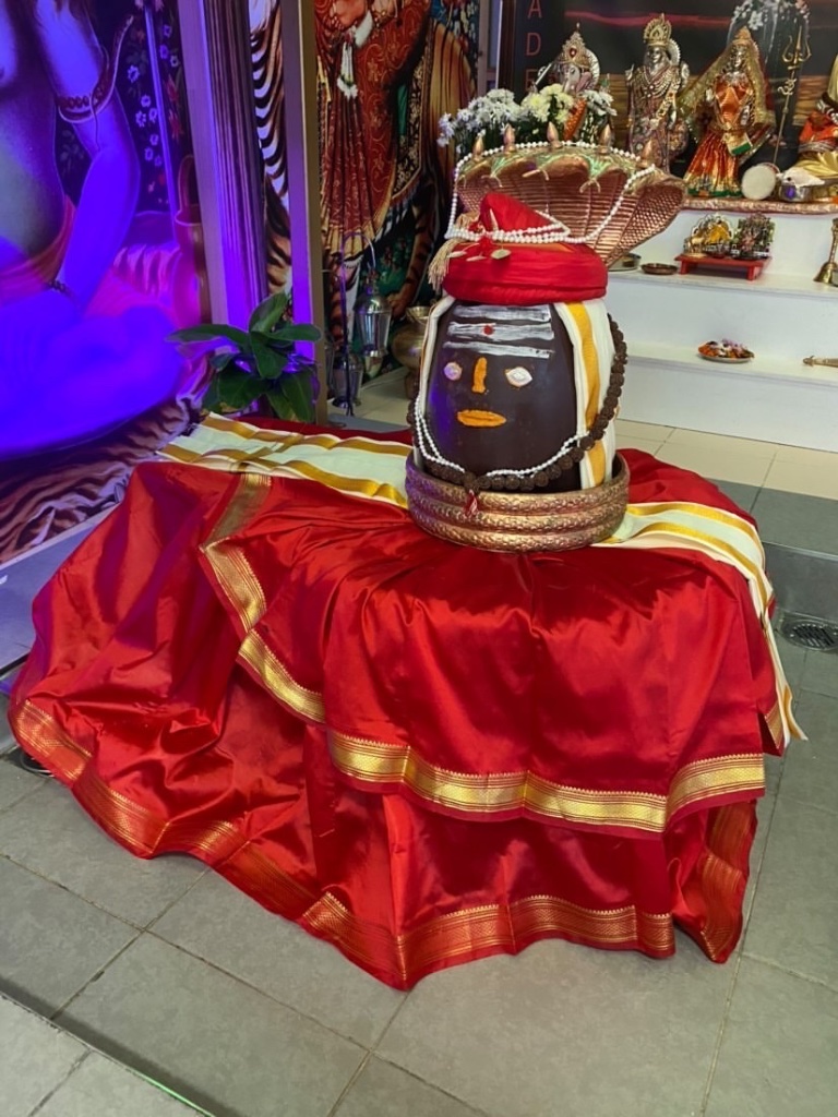 The Lingam adorned with a sacred face, crowned with a red turban and draped in silk.