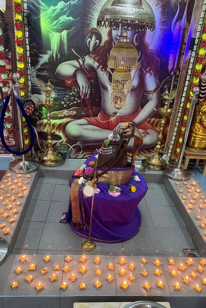 The shrine surrounded by rows of glowing oil lamps during a festival.