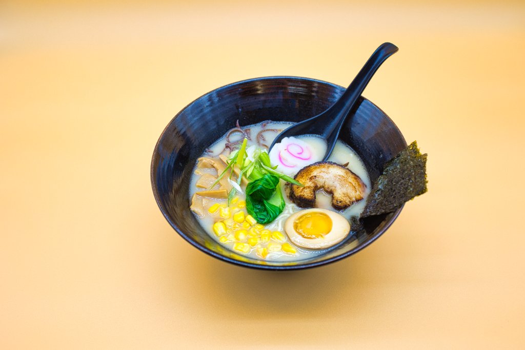 Ramen with corn, pork and egg on orange background