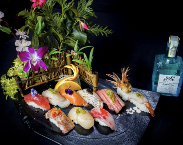 Premium nigiri sushi platter with orchids and sake
