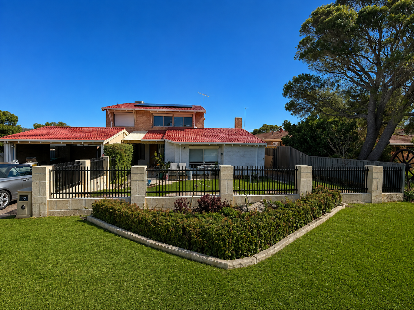 Green lawn with brick-bordered garden bed and pillared fencing