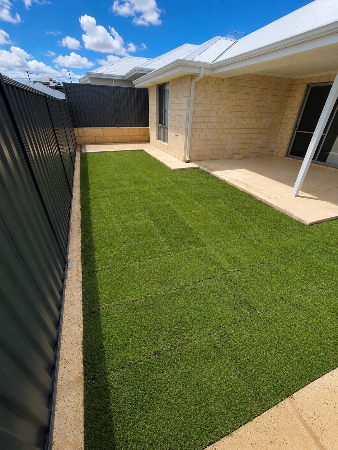 Freshly laid roll-on turf with brick edging