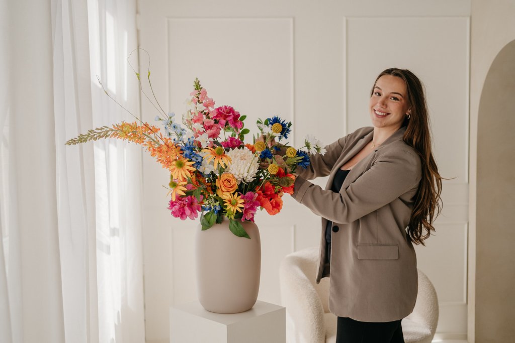 Bianca Rijkenbarg met kleurrijk bloemstuk in witte ruimte
