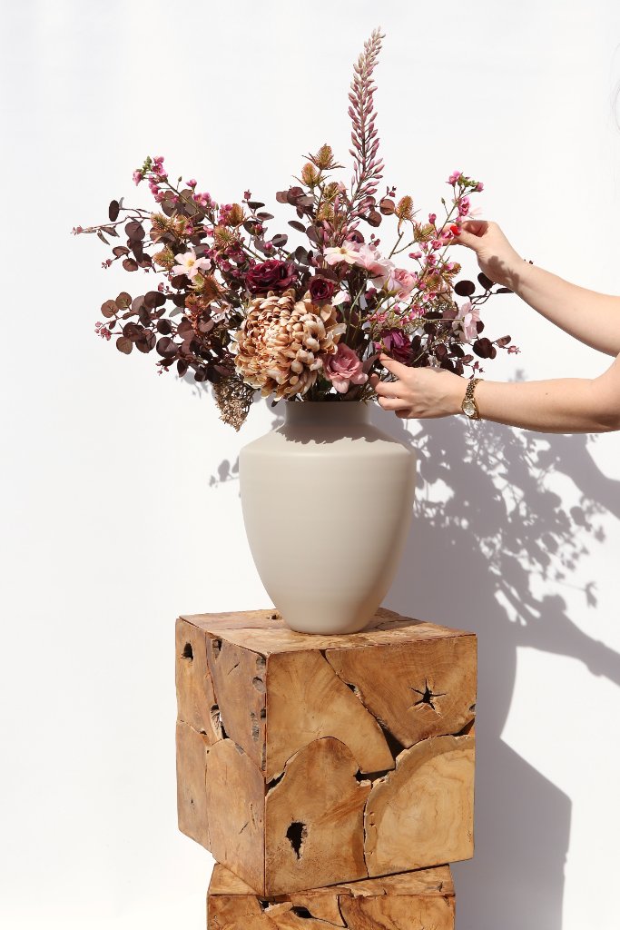 Kleurrijke bloemen in gouden vaas op houten tafel