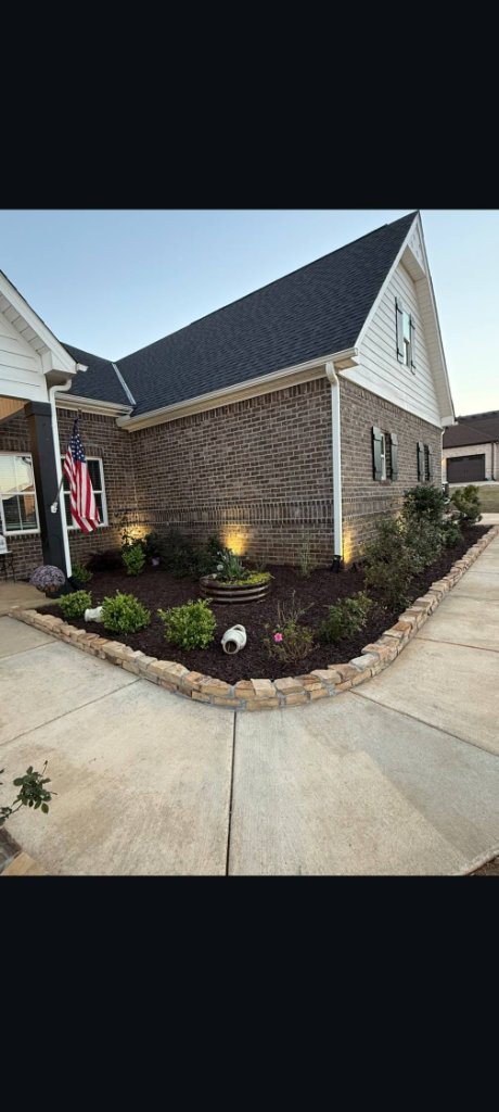 Landscaped front yard with stone retaining wall and mulch beds by Slava LLC in North Alabama