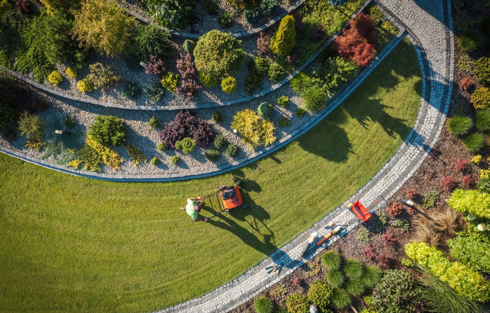 Landscaper mowing a manicured garden, seen from above