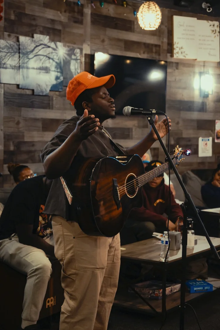 A musician leading worship with acoustic guitar at Saturday Sanctuary