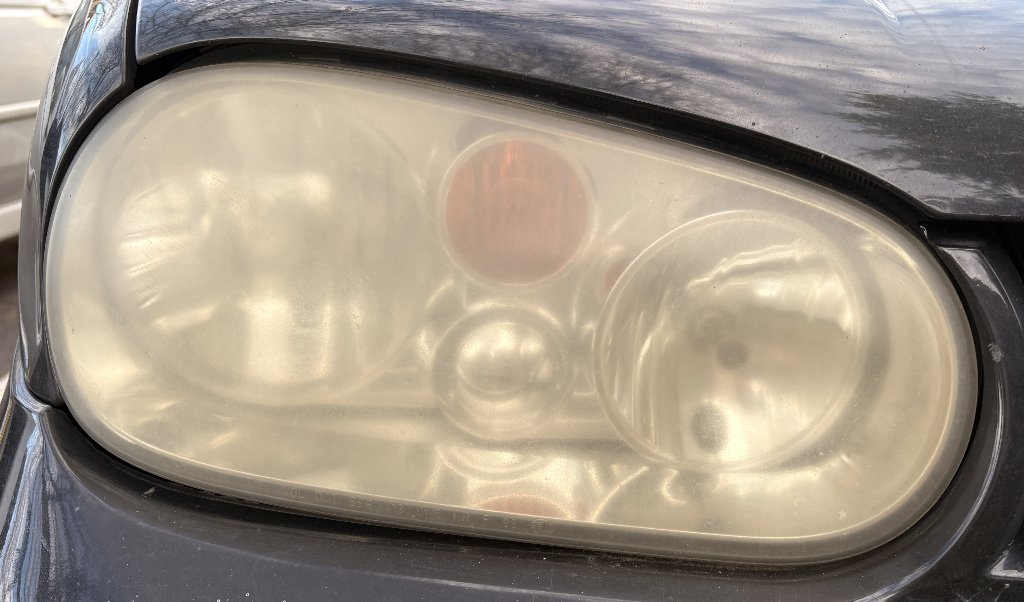 VW headlight before restoration — oxidized, yellowed, foggy headlight lens reducing visibility