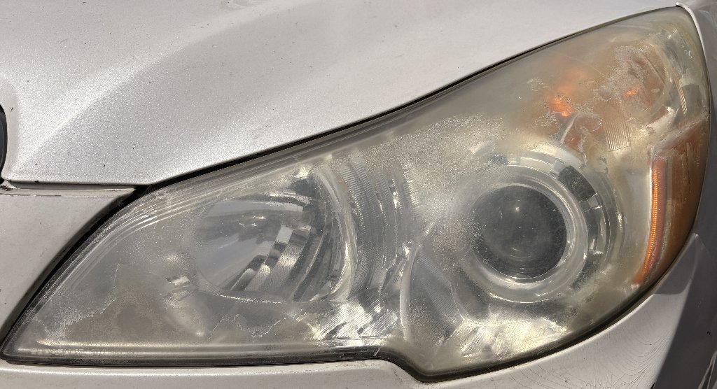 White SUV headlight before restoration — foggy, oxidized, yellowed headlight lens in Tigard, OR