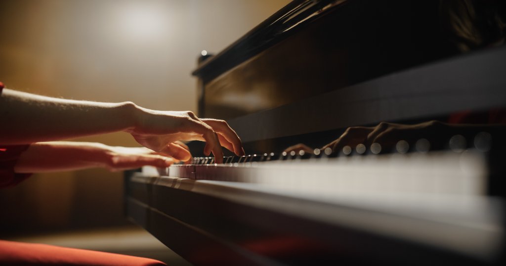 Hands playing piano keys with dramatic lighting