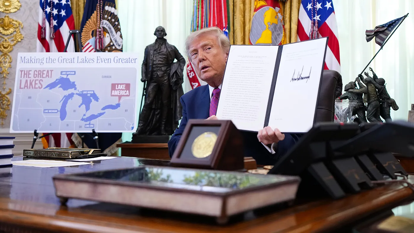 President Donald Trump holds up the signed executive order renaming Lake Ontario as Lake America in the Oval Office.