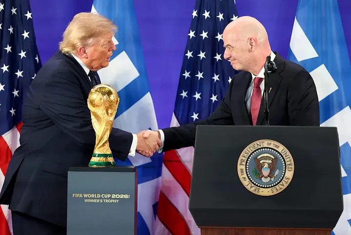 President Donald Trump and FIFA President Gianni Infantino shake hands beside the FIFA World Cup trophy