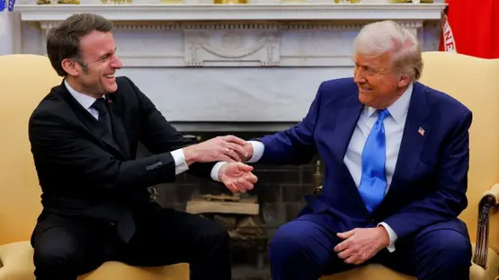 Emmanuel Macron and Donald Trump shake hands in a formal meeting room.