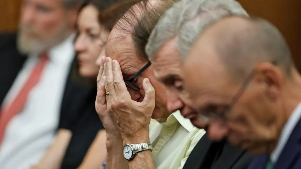 A man in a yellow shirt covers his face inside the Plymouth Superior Courtroom
