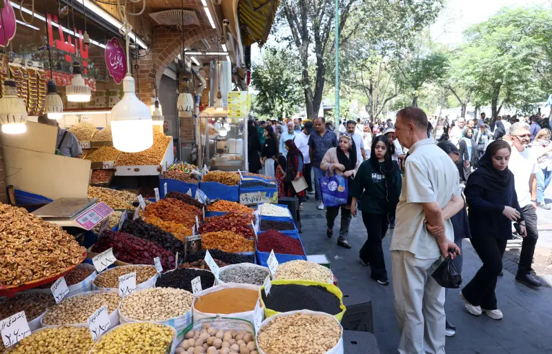 Iranians shopping at a Tehran bazaar with bins of nuts and dried fruits