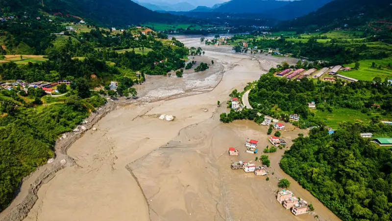 Aerial view of flood-stricken river valley in Nepal with partially submerged buildings