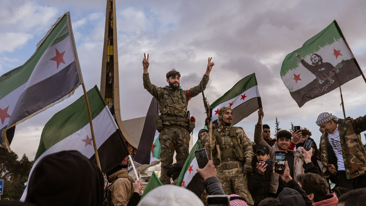 Crowds celebrating in Syria holding the opposition flag after the fall of Bashar al-Assad