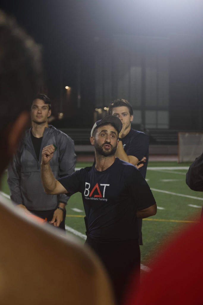 BAT coach instructing athletes on the field at night